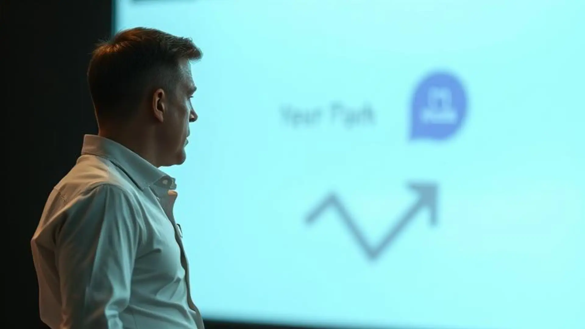 Industrievertrieb mit Powerpoint: Mann steht vor einer großen Leinwand im Sales-Pitch und versucht seine Maschine und Produkte zu erklären